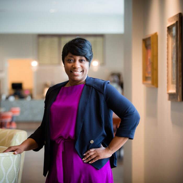Corporate portrait of a Norterre team member, on-location near framed artwork and a café seating area.
