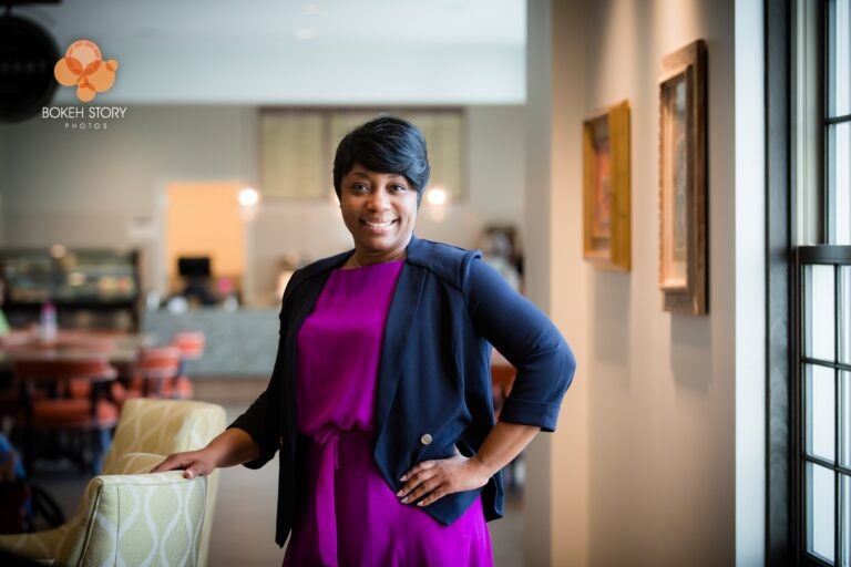Corporate portrait of a Norterre team member, on-location near framed artwork and a café seating area.