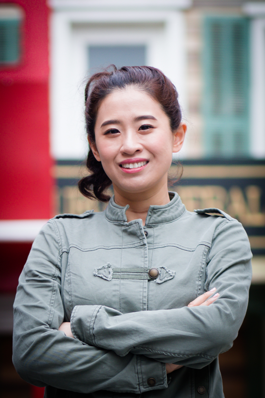 Lai Xu smiling outdoors in a gray jacket.